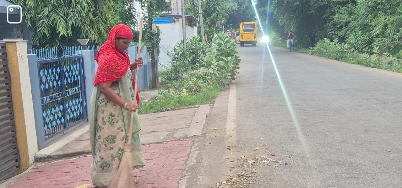 Sanitation worker sweeping the road near a house during a cleanliness drive in Bhopal.